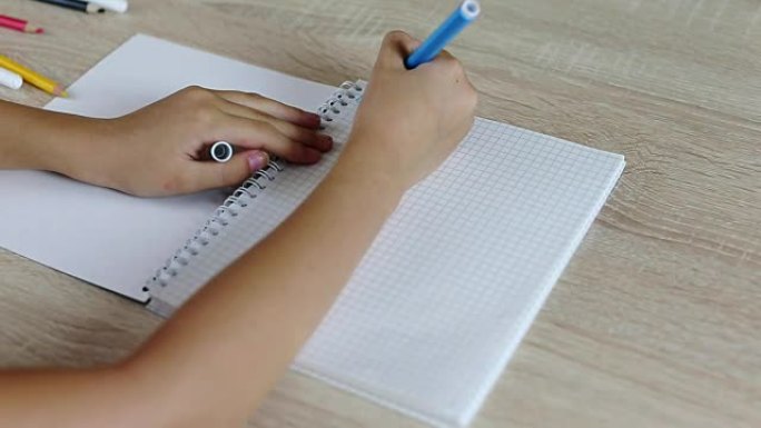 年轻女孩用纸质笔记本写信回学校。年轻女孩坐在桌边。白人女孩写信有误。用毡笔纠正错误。在家工作的女学生