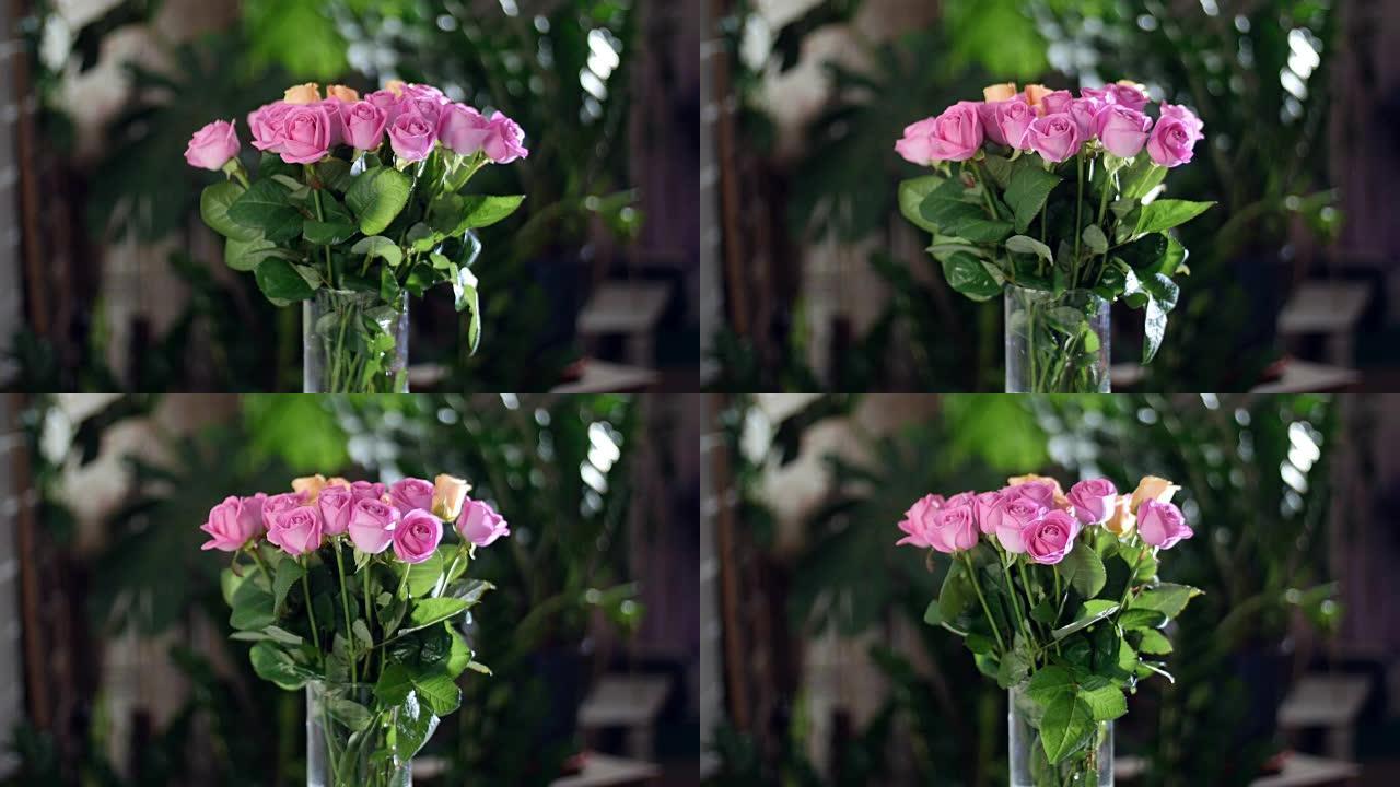 花束在光线中，旋转，花卉组成由粉红色和橙色玫瑰水色组成。背景中有很多绿色植物。神圣之美