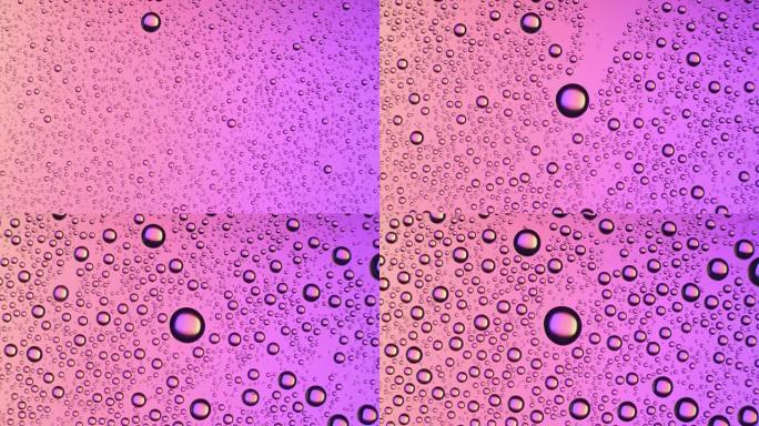 水滴出现在粉红色背景的玻璃表面上