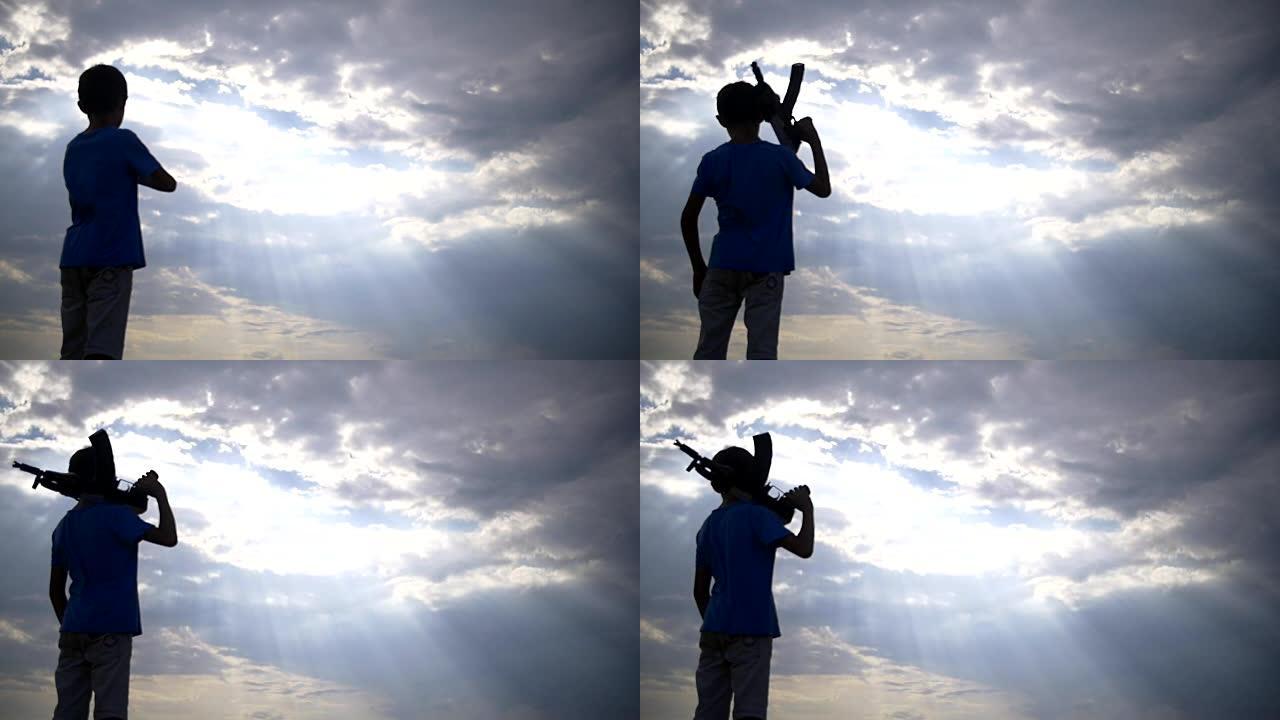 日落时拿着枪的男孩在乌云的背景下，ak 47