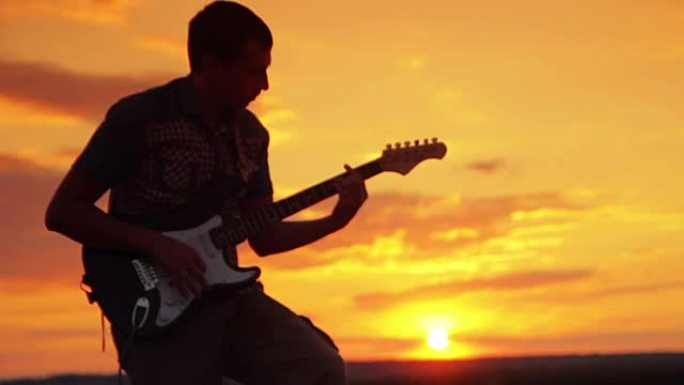 吉他手在夕阳下的温暖夏日傍晚在阳光下演奏摇滚