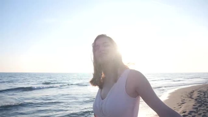 美丽的女人在沙滩上拿着轻盈的布料享受日落