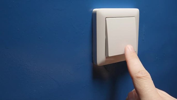 人手关闭蓝色墙壁上的电源按钮-侧视图
