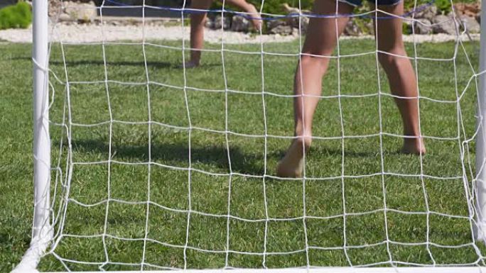 孩子们在绿色草坪上踢足球。赤脚儿童踢球
