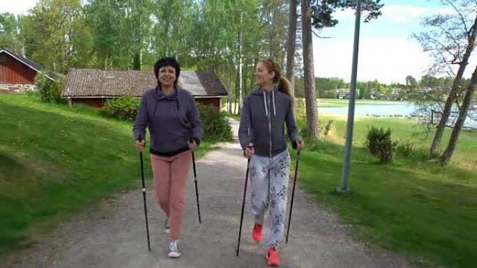 两个活跃的女人在公园里做北欧散步。跟踪镜头
