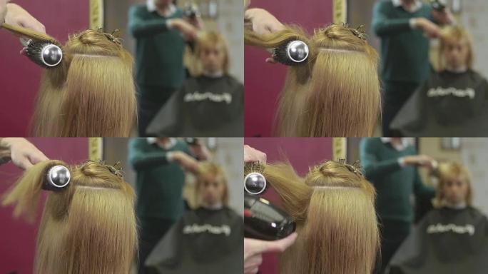 理发师在美容院用梳子和吹风机铺上女孩的头发。制作体积发型。镜子