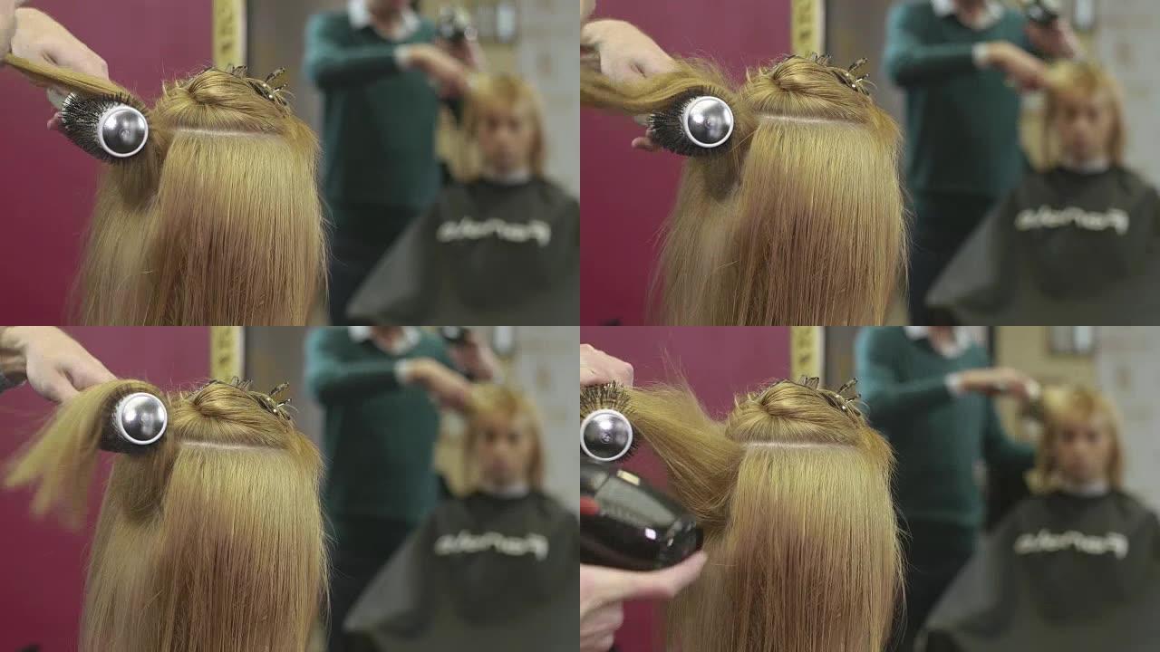理发师在美容院用梳子和吹风机铺上女孩的头发。制作体积发型。镜子