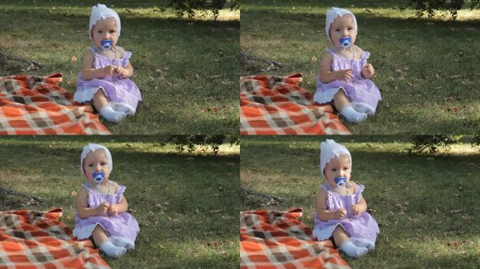 一个用毯子坐在草地上的奶奶子的女婴