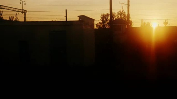 黎明时从火车窗口观看。有树木、车站建筑和货车的轮廓