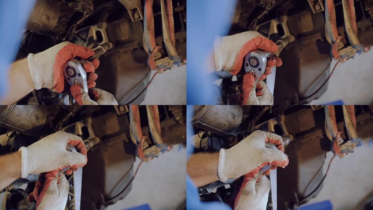 机械师用悬挂在修理厂的汽车马达船体上的工具拧紧螺栓。