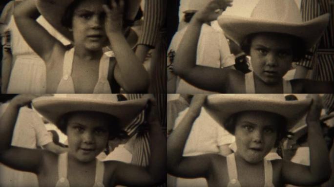 1937: 可爱的女孩在皮革牛仔帽擦汗从脸弯曲的帽子。