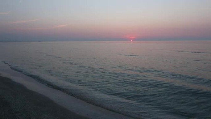 太阳升起在地平线和蓝粉色海面上。