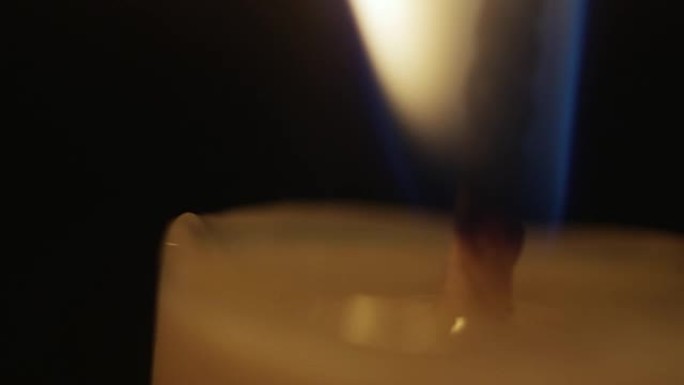 黑色背景上蜡烛火焰的特写。烛芯的宏观拍摄。慢动作