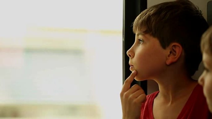 坐火车旅行的小男孩。孩子看着火车窗外。孩子在火车窗外观察