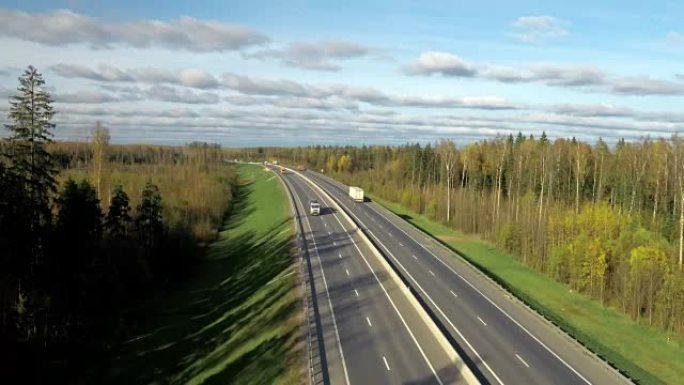 在森林和天空背景下在公路或公路上行驶的现代汽油车的鸟瞰图