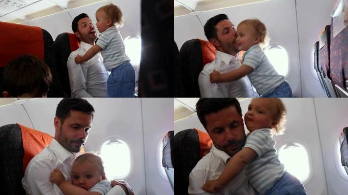 父亲带着孩子和婴儿乘飞机旅行。爸爸在等待飞机起飞时抱着婴儿玩耍