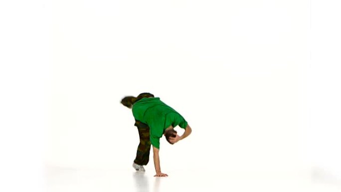 穿着绿色衬衫的年轻舞者男子在白色上跳霹雳舞