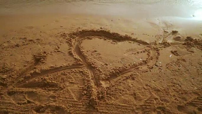 心沙。心在沙子上画画。沙子背景上的心形