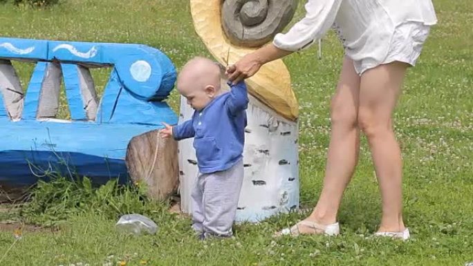 男婴在妈妈的支持下在公园散步