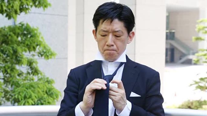 严肃的日本成熟男人带着紧张的表情打领带
