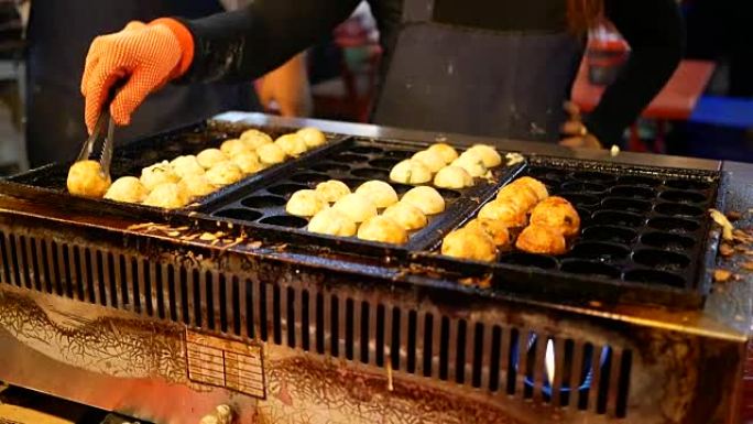 身份不明的女人在夜市中烹饪章鱼烧