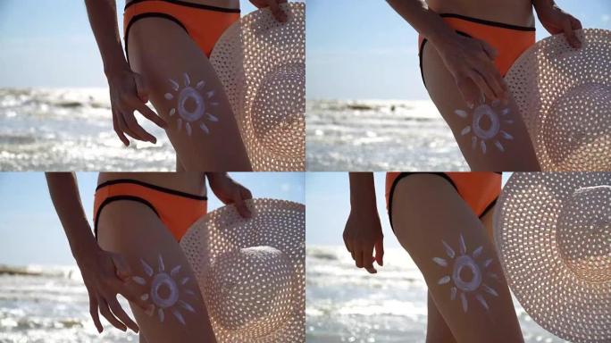 年轻女子站在沙滩上，在腿上画太阳