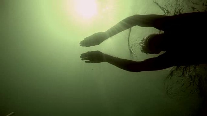 运动员在太阳反射水面和水下POV的情况下游泳。