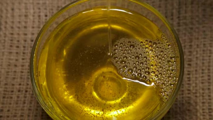 特写旋转的玻璃碗中的葵花籽油。