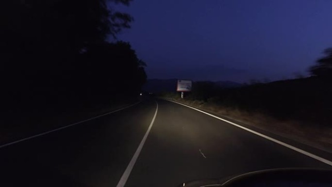 在漆黑的夜晚在乡村道路上行驶，大灯打开，pov
