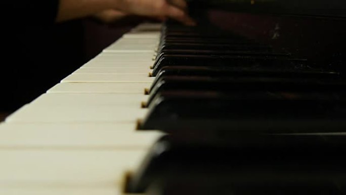 女性的手在优美的三角钢琴上演奏着轻柔的古典音乐。弹钢琴的女人，特写。