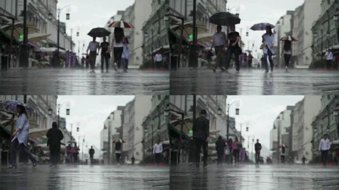 城市街道雨天的背景。实时。雨中带伞的人上下班。拿着五颜六色雨伞的年轻女孩。模糊的波克。自然背景