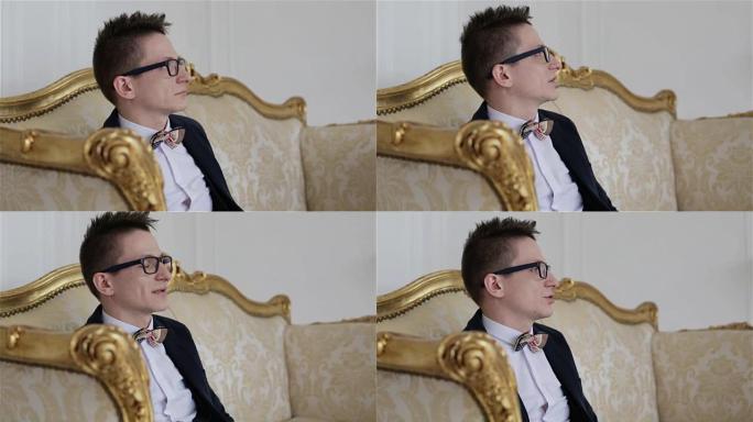 戴眼镜的年轻迷人男人坐在金色沙发上聊天。