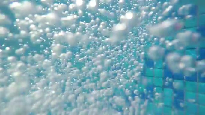 气泡上升到表面。慢动作。泳池清澈蓝色水中的气泡 (水下拍摄)，适合背景