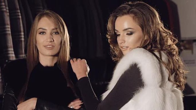 两位女士在精品店里穿着丰富的毛皮大衣摆姿势做广告。慢慢地