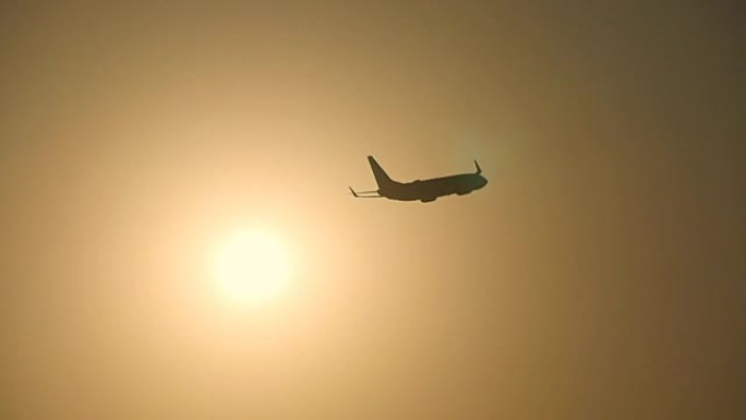 日落时，客机的轮廓飞过太阳。飞机在日出背景下起飞。飞机在美丽的早晨天空穿越sunrais。慢动作特写