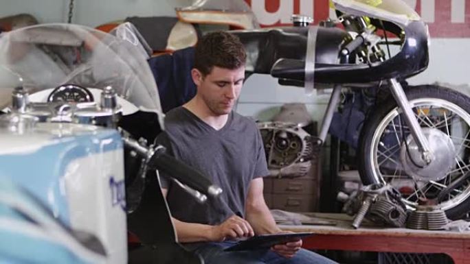 男子在摩托车附近使用平板电脑