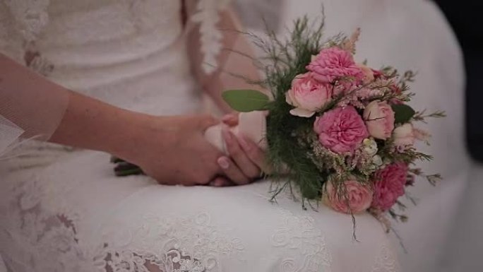新娘手中的新娘美丽花束，白色婚纱