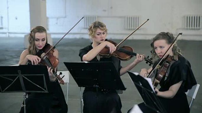三个女孩在管弦乐队的大提琴上演奏
