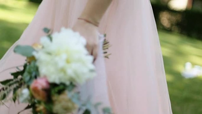 美丽的婚礼花束，白色和粉红色的玫瑰在新娘的手中，走在户外