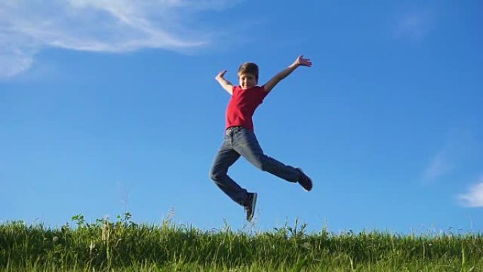 快乐男孩在绿草山上跳跃，对抗蓝天