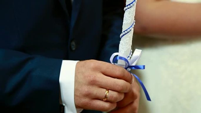 仪式上，新郎和新娘手里拿着浓密的白色蜡烛