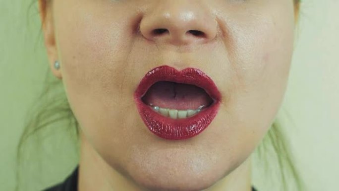嘴唇上有红色发油的女人在前置摄像头中唱歌。口。牙齿