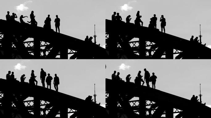 年轻人在桥顶上不稳定的情况下漫步并互相拍照的剪影