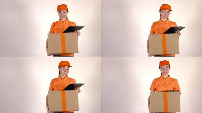 穿着橙色制服的女孩快递员送一个大纸箱。浅灰色背景，全高清工作室拍摄