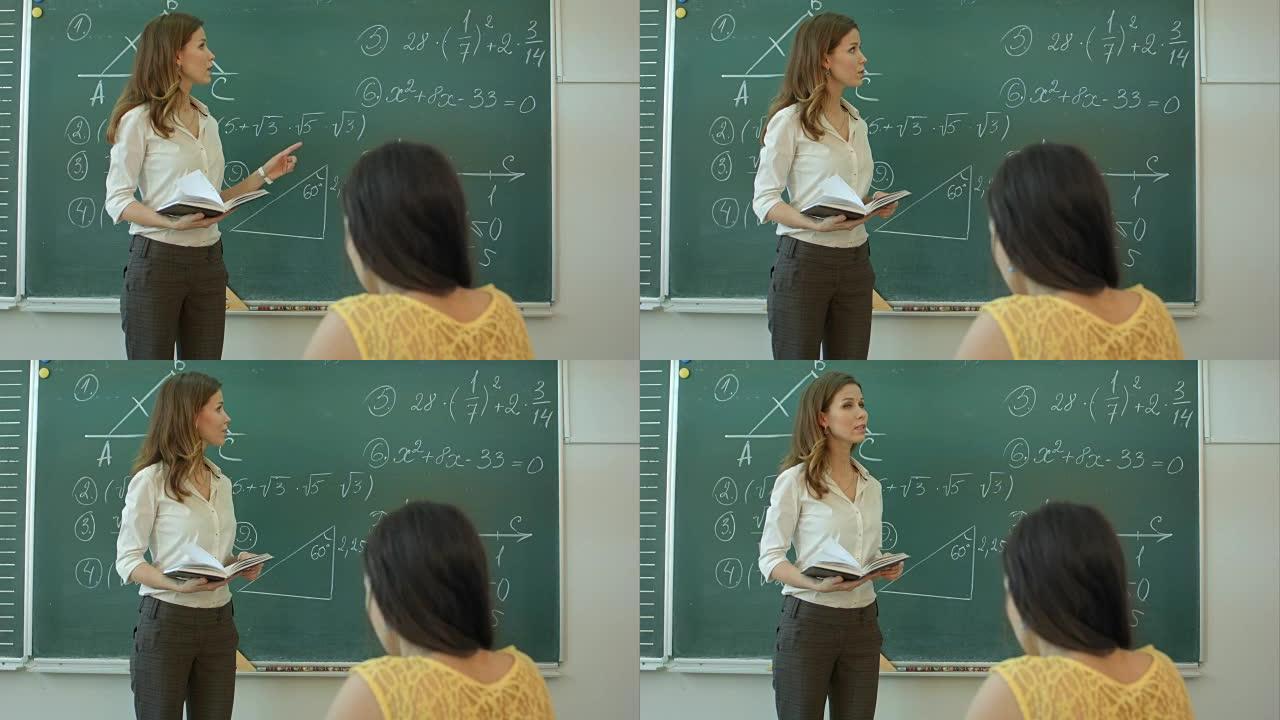 数学课上有吸引力的年轻女老师站在黑板前讨论