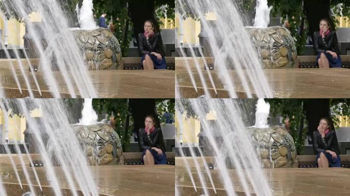 一个悲伤美丽的女孩坐在公园里，靠近喷泉。坏消息，绝望和渴望。