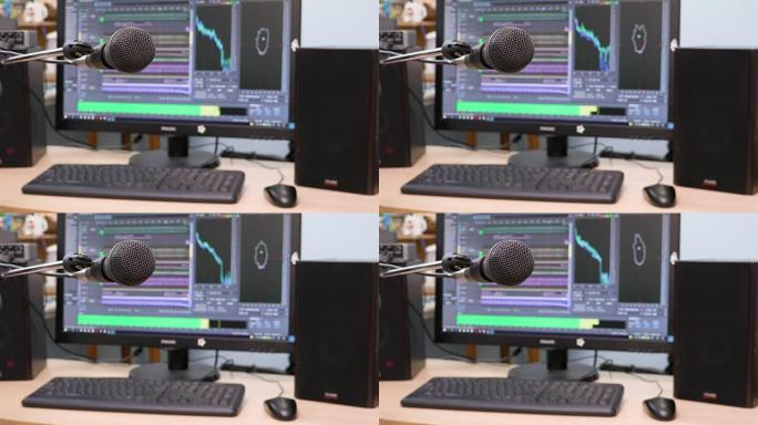 电脑显示器背景上的麦克风。家庭录音棚。特写。前景中的焦点。背景模糊。用于记录和编辑声音的软件。4K，