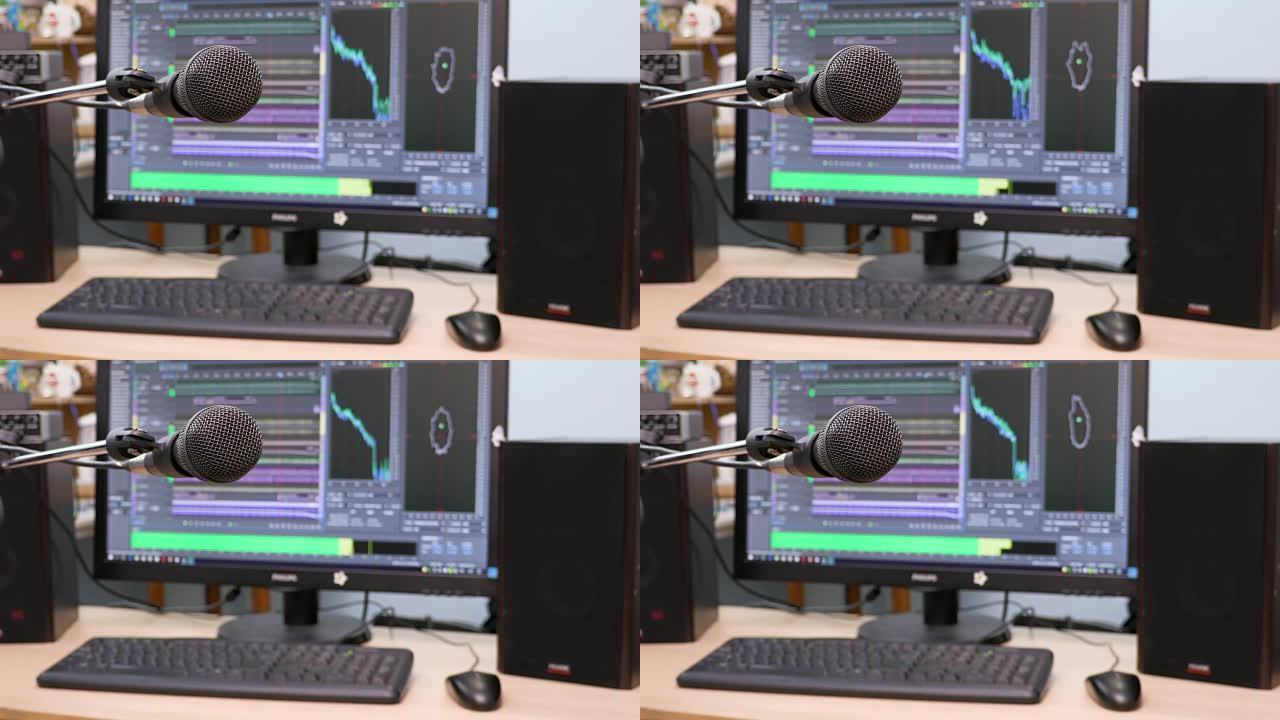 电脑显示器背景上的麦克风。家庭录音棚。特写。前景中的焦点。背景模糊。用于记录和编辑声音的软件。4K，