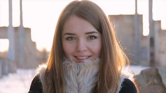 在废弃建筑物的背景上穿着羊皮大衣的女孩。慢动作