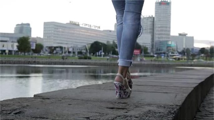 一个穿着牛仔裤和坡跟鞋走路的女人。慢动作。